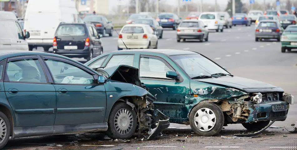 Two heavily damaged green cars after a road collision with traffic in background, representing concussion settlements in car accident cases