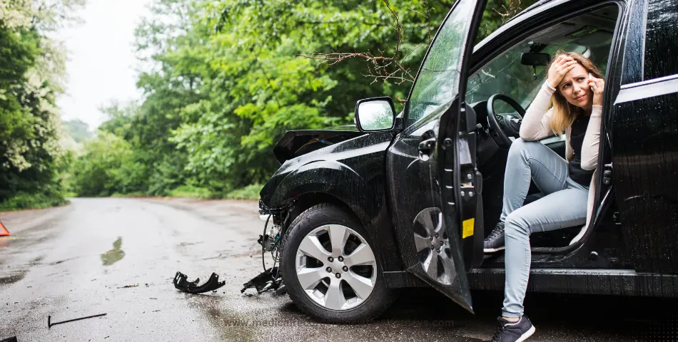Distressed woman sitting in a crashed black car on a wet road, representing the odds of dying in a car crash and accident risks