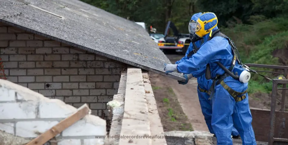 Worker in blue hazmat suit and respirator removing roofing material, representing asbestos exposure risks and related legal claims