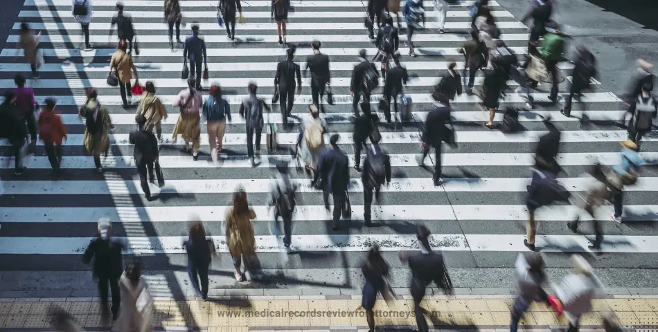 Crowd of pedestrians crossing busy zebra crosswalk in city during daytime, illustrating injured while crossing scenario