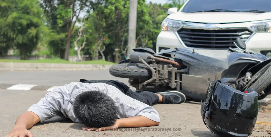 Man lying on road beside fallen motorcycle and helmet representing motor vehicle accident cases