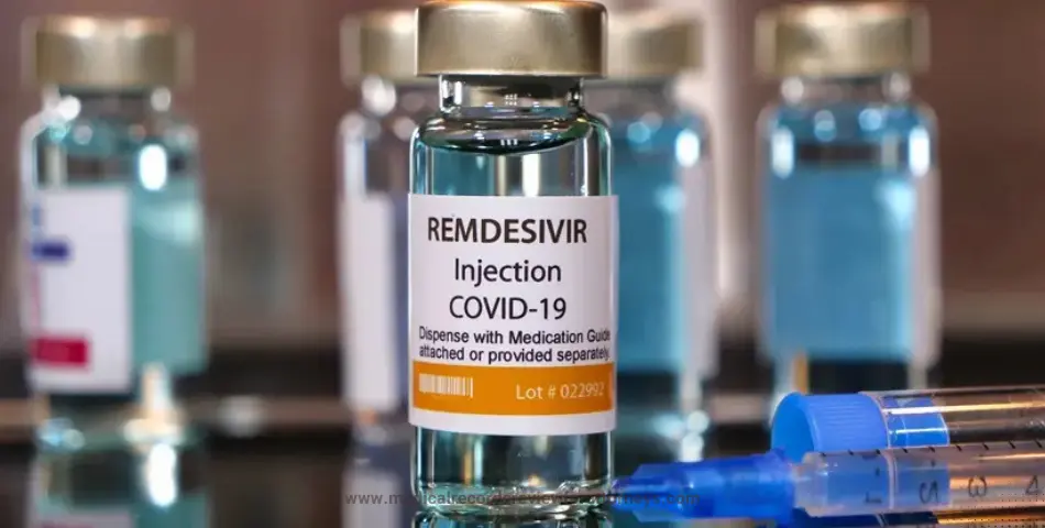 | Close-up of a Remdesivir injection vial labeled for COVID-19 treatment with syringes nearby on a reflective surface represents remdesivir lawsuits.